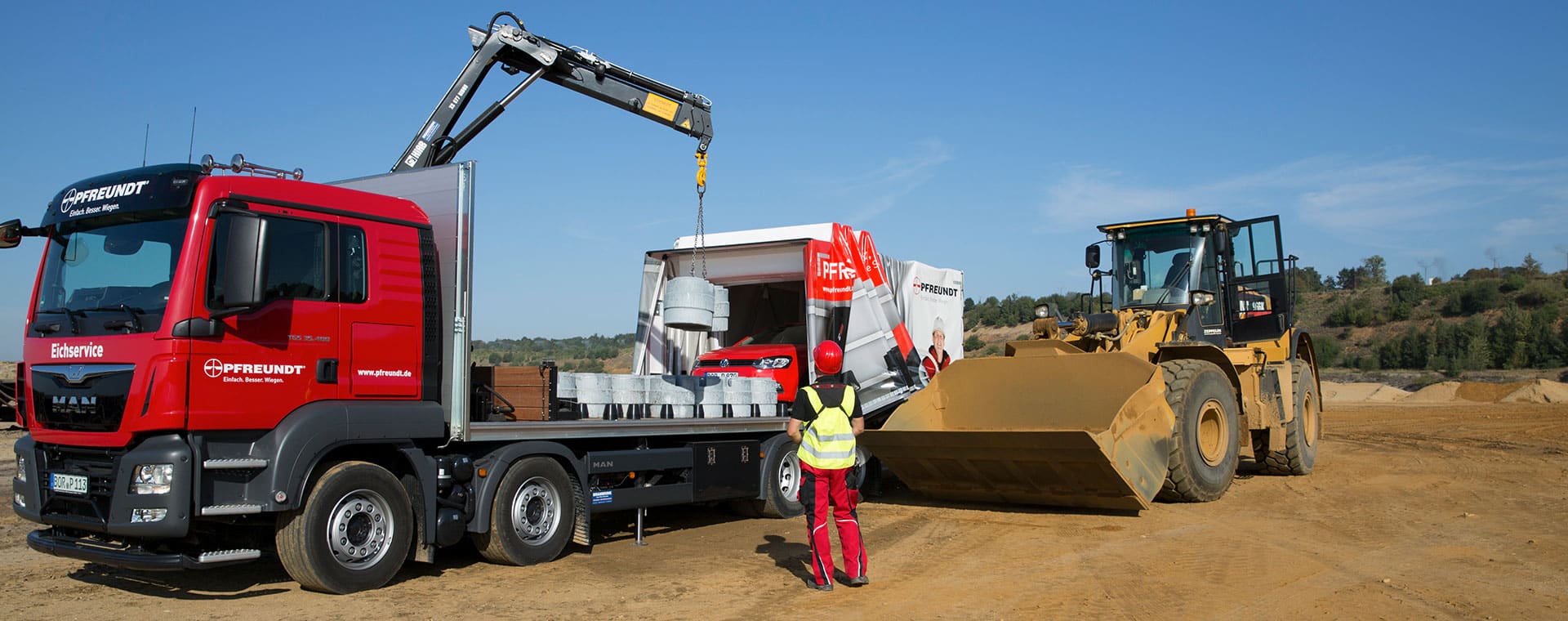 A PFREUNDT truck and wheel loader working with mobile weighing systems on a construction site.