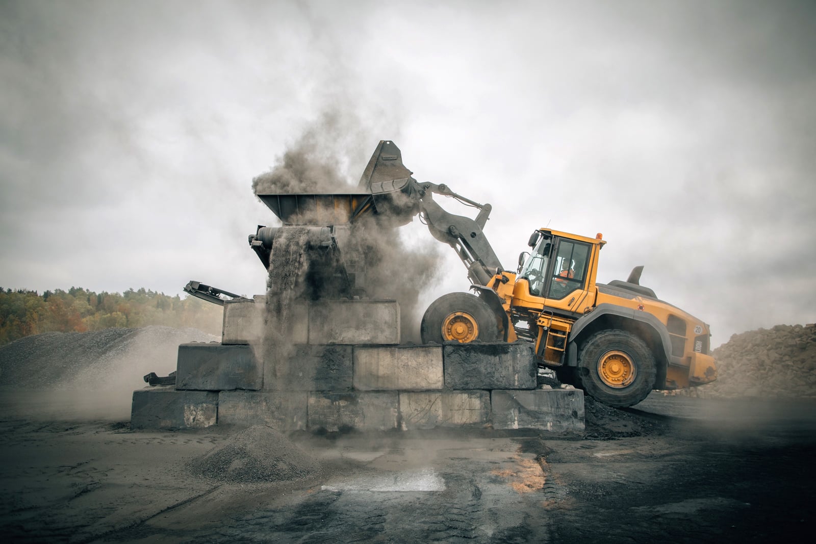 Yellow wheel loader unloading material on an outdoor construction site. PFREUNDT mobile scale in use for precise measurements.