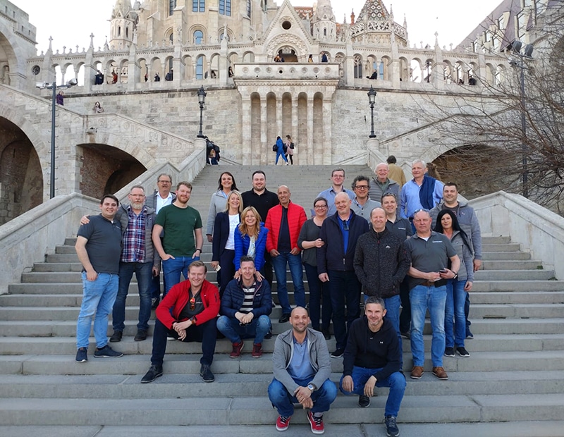 Group of PFREUNDT employees on a staircase in front of historic architecture. Provider of mobile weighing systems.