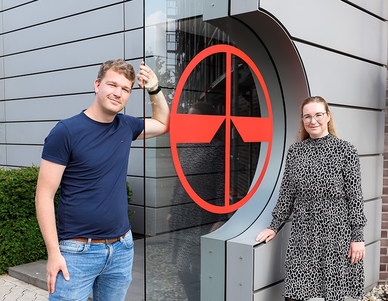 PFREUNDT company logo on the wall with two people in front of it. Provider of mobile weighing systems such as excavator and crane scales.