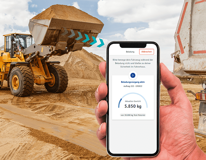 Man holding a smartphone with a weighing app while a wheel loader loads sand onto a truck. PFREUNDT mobile weighing systems.