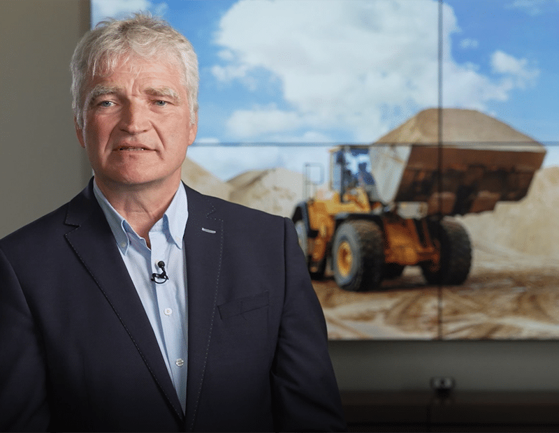 Ludger Wissing beim Video-Statement vor einem Bildschirm mit Radlader.