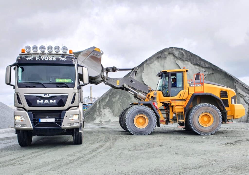 LKW und Radlader mit PFREUNDT Wiegesystemen beim Schüttguttransport auf Baustelle.