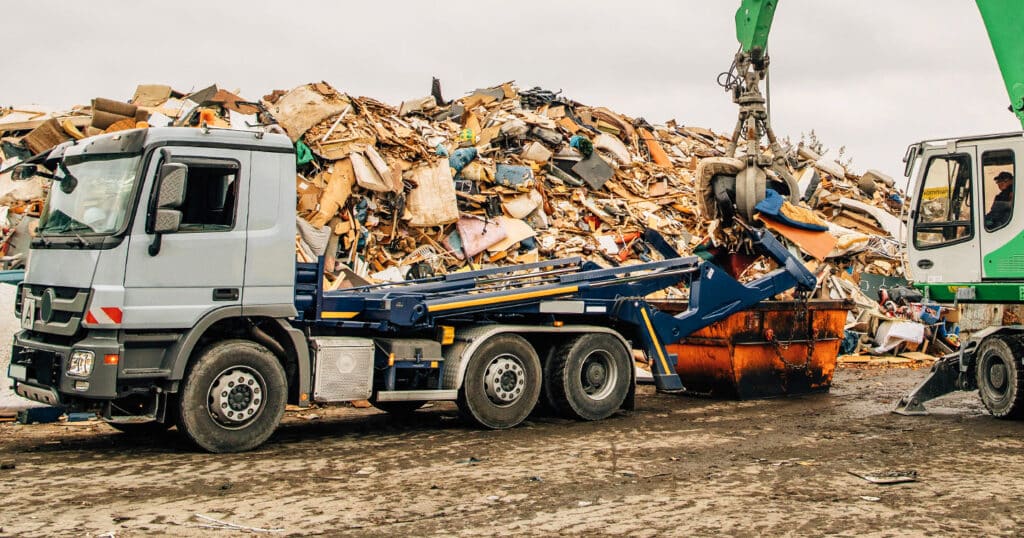 Skip loader with PFREUNDT skip loader scale in front of a large pile of scrap.