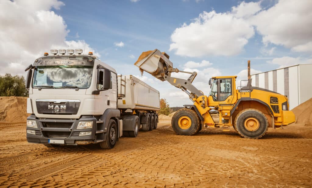 Radlader belädt einen LKW mit Sand – Einsatz des PFREUNDT Überlast-Kontrollsystems.