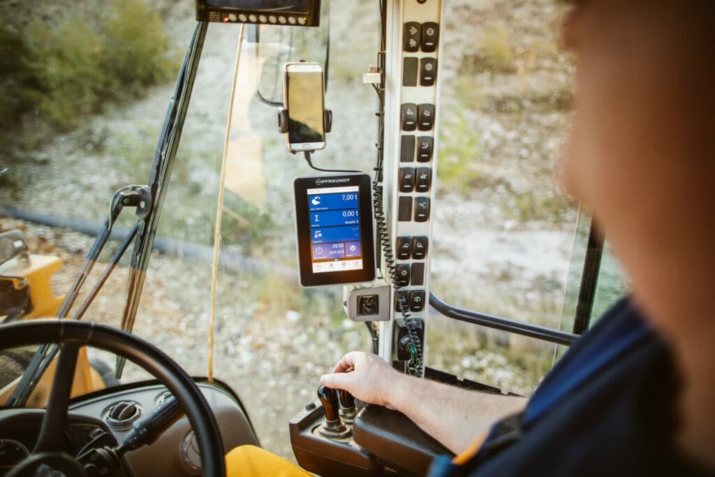Cab of a vehicle with PFREUNDT on-board computer for mobile weighing, driver’s hand on the lever.