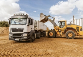 A wheel loader loads a lorry on a building site, demonstrating PFREUNDT’s mobile weighing technology for efficient material transport.