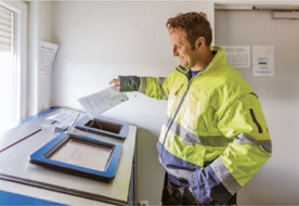 An employee in a yellow jacket carries out data processing at PFREUNDT, which specialises in mobile weighing systems.