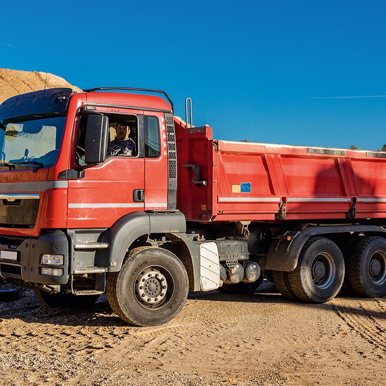 Red dump truck with PFREUNDT Overload Control System on a construction site.