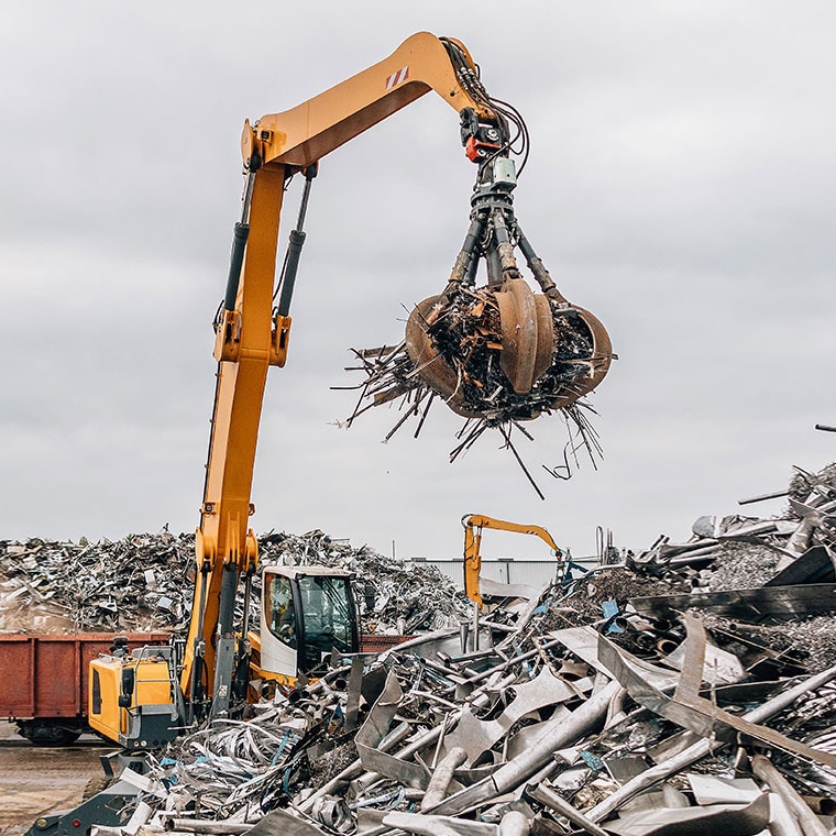 Material handler with PFREUNDT Material Handler Scale lifting scrap with its grapple at a recycling site.
