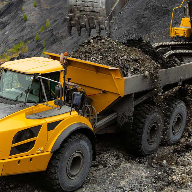 Gelber knickgelenkter Dumper mit PFREUNDT Dumperwaage wird im Steinbruch beladen.