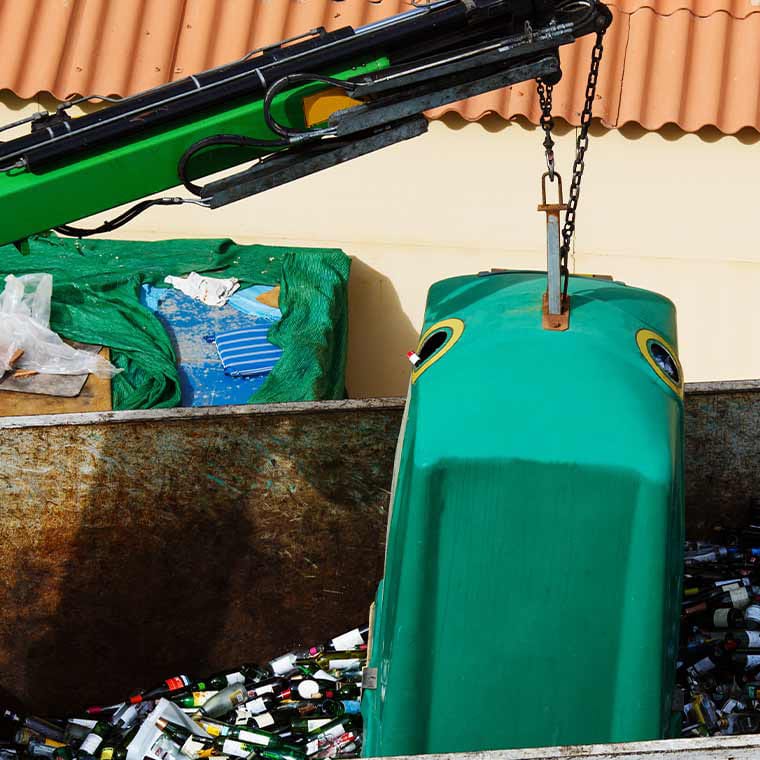 Grüner Ladekran mit PFREUNDT Kranwaage hebt einen Glascontainer.