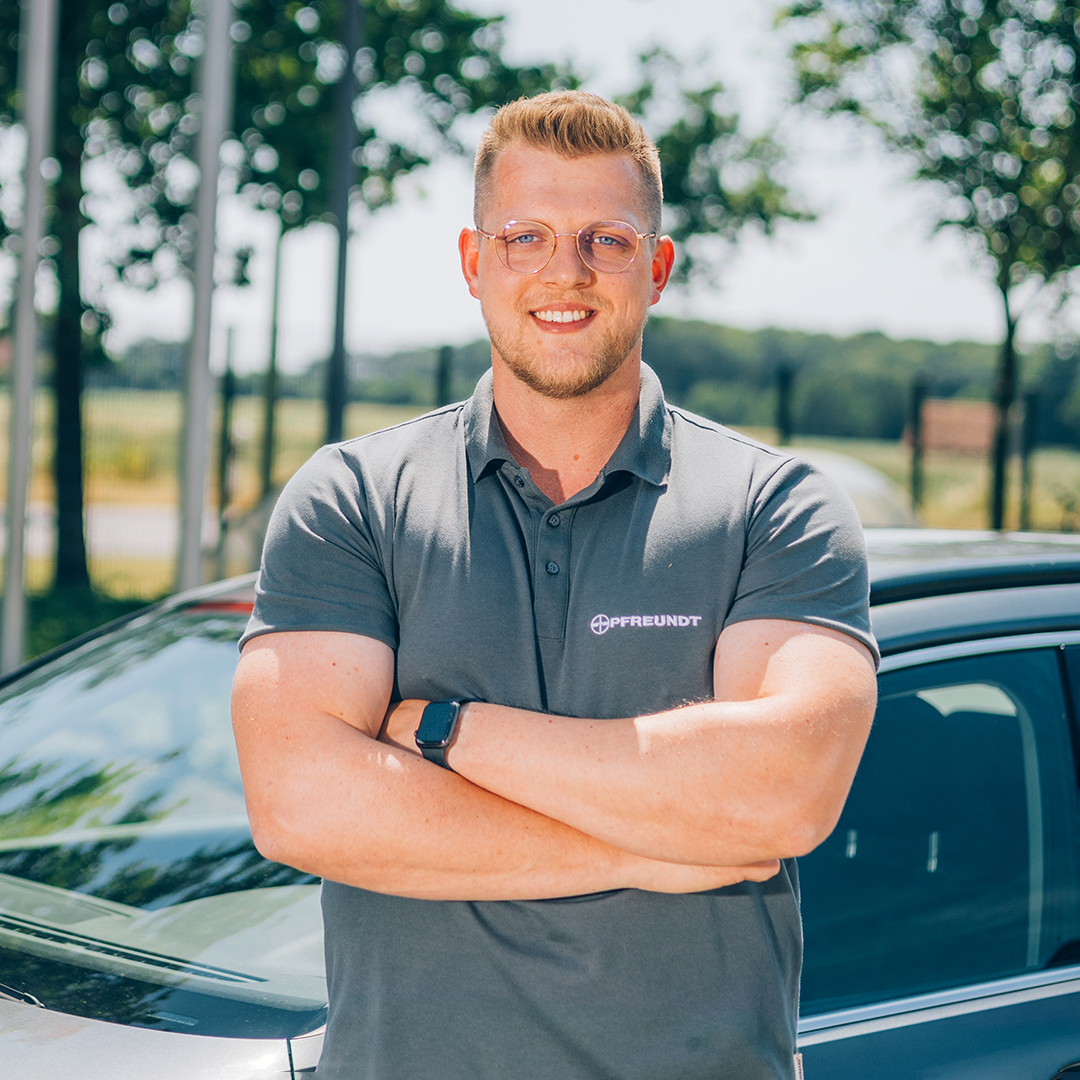 Man in a PFREUNDT polo shirt in front of a car; PFREUNDT supplies mobile weighing systems.