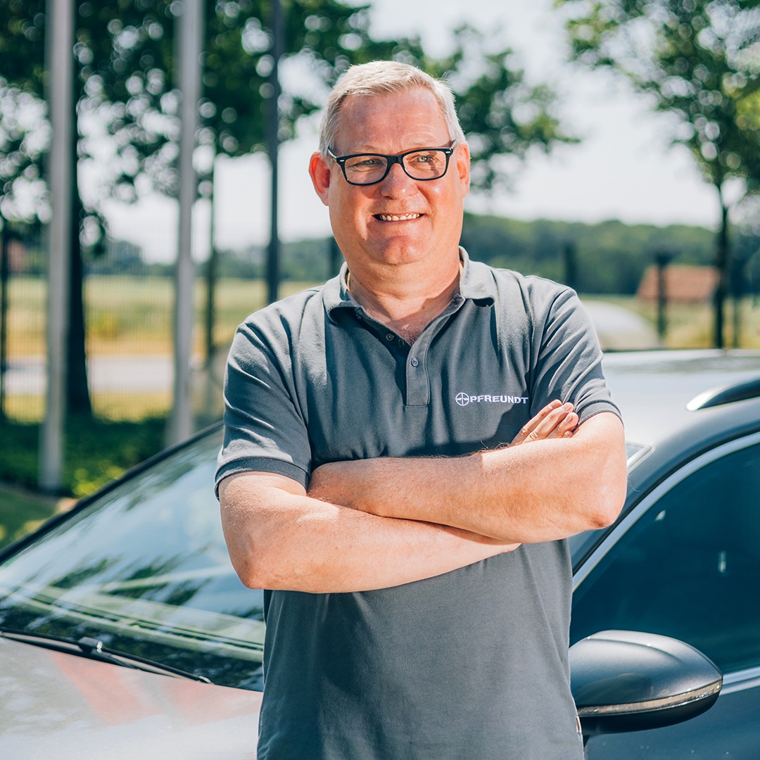 Mann in PFREUNDT bietet diverse mobile Wiegesysteme an.-Polohemd lächelt vor Auto im Freien. PFREUNDT bietet diverse mobile Wiegesysteme an. bietet mobile Wiegesysteme für verschiedene Anwendungen.