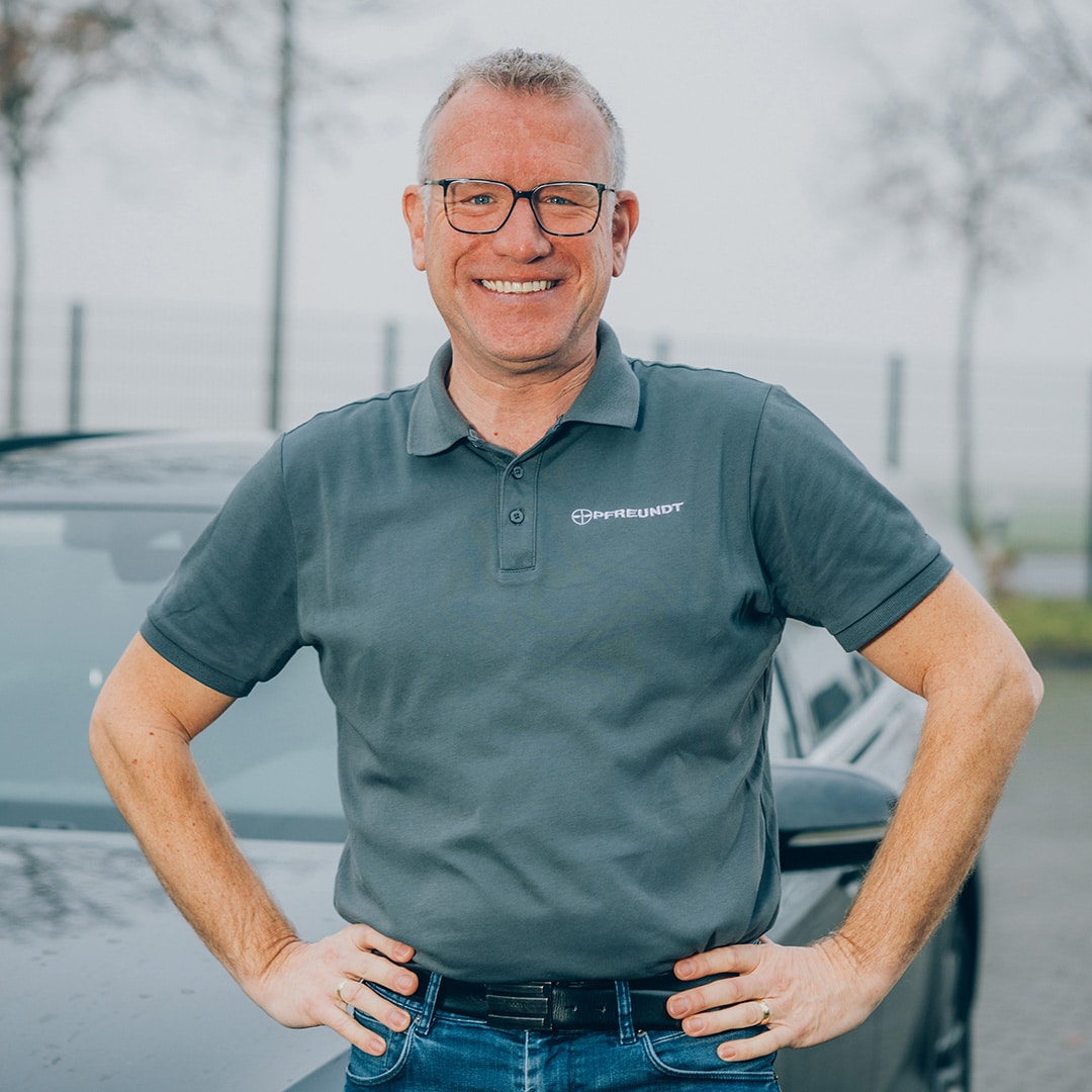 Mann im PFREUNDT bietet diverse mobile Wiegesysteme an.-Shirt vor einem Auto, draußen. PFREUNDT bietet diverse mobile Wiegesysteme an.