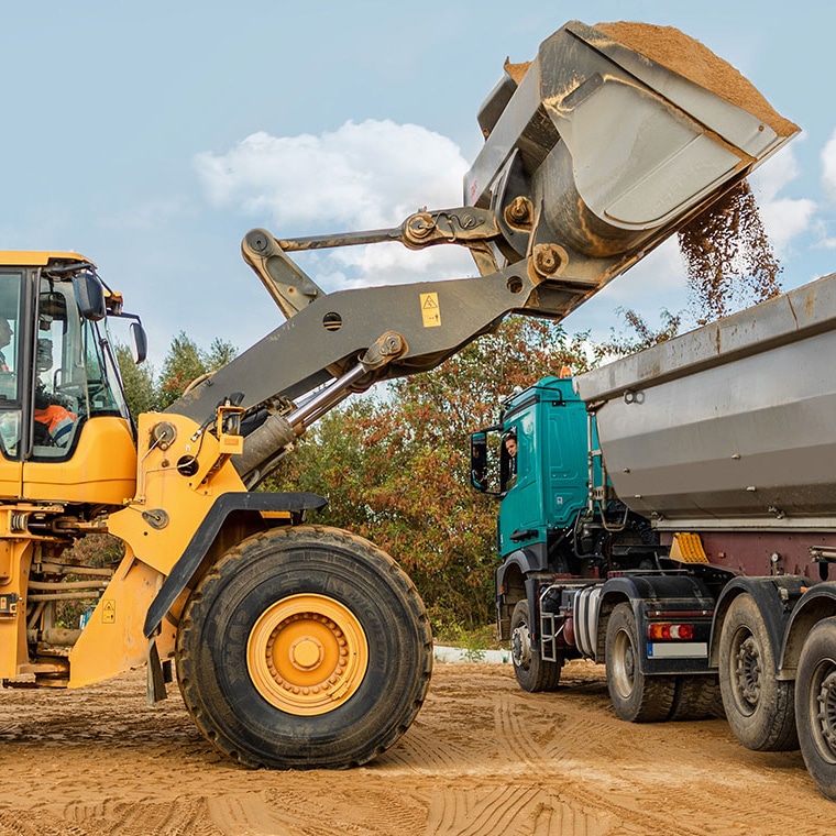 Wheel loader with PFREUNDT Wheel Loader Scale loading a truck on a construction site.